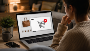 Pessoa realizando compras online em notebook e interrompendo a finalização do pedido, representando abandono de carrinho, perda de conversões e desafios na experiência do usuário em e-commerce.
